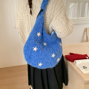 Blue plush shoulder bag with white star pattern worn with a cozy winter knit sweater