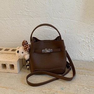 Detail of dark brown lychee grain leather bucket bag with silver lock and plush bear