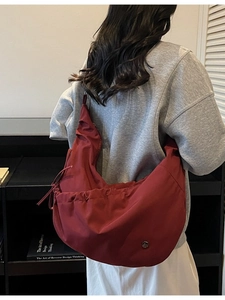 Minimalist burgundy nylon crescent shoulder bag with drawstring and metal logo