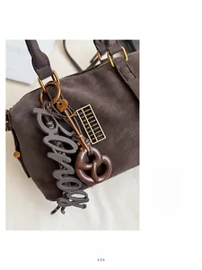 Close-up of retro brown leather handbag featuring golden hardware and diverse charms