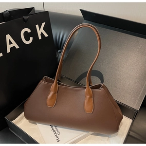 Close-up of brown pebbled leather tote bag displayed in a gift box with a shopping bag