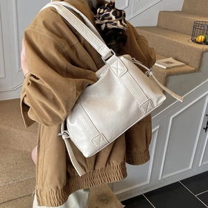 Close-up of cream-white leather tote bag with silver hardware and reinforced stitching