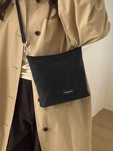 Schicke schwarze Trapez-Schultertasche aus mattem Stoff zum Trenchcoat gestylt