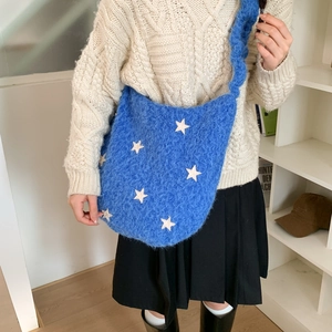 Detail of blue plush shoulder bag with white star patterns and soft textured strap
