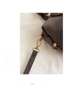 Detail of high-quality gold metal hardware and pebbled leather on brown Boston bag