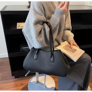 Close-up of black lychee grain tote bag held by model in minimalist lifestyle setting