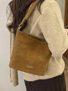 Braune Wildleder-Schultertasche für Damen mit Gold-Schnalle und Markenplakette in Innenräumen