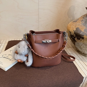 Détail du sac seau en cuir grainé marron foncé avec fermoir rotatif argenté et breloque