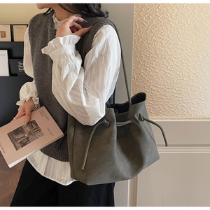 Detail of olive green tote bag with drawstring knot on textured faux leather