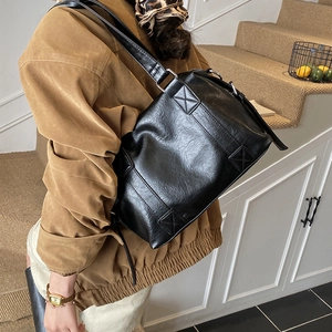 Detail of black pebbled leather tote bag showing wide strap and silver metal hardware