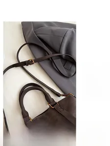 Detail of adjustable shoulder strap and gold hardware on a dark brown Boston bag