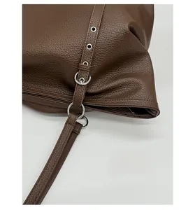 Close-up of brown lychee grain leather tote with adjustable strap and silver metal buckle
