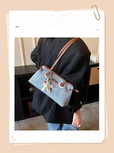 Détail du sac en jean avec lanières en cuir marron et pendentif étoile