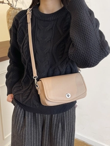 Bolso de hombro minimalista de cuero beige con textura granulada y cierre de giro