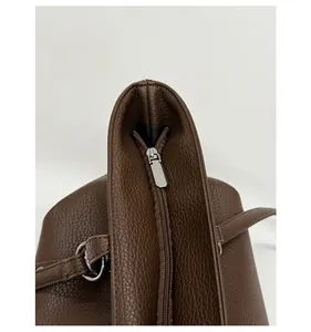 Detail of smooth silver zipper and lychee texture on dark brown leather tote bag