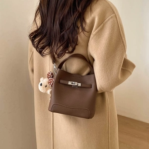 Detail of dark brown leather bucket bag with silver lock and plush bear charm