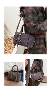 Detail view of brown Boston bag with retro charms and adjustable shoulder strap