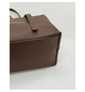 Detail view of reinforced base on brown lychee pattern leather tote bag with clean stitching
