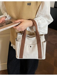 Minimalist canvas tote bag with brown straps and multi-pocket design for daily commute