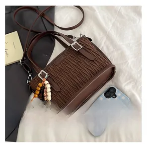 Détail du sac plissé marron vintage avec charme en perles et boucle en métal argenté