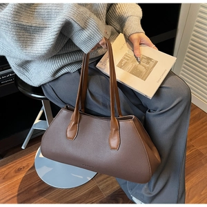 Close-up of the dark brown lychee leather texture and minimalist logo on the tote bag