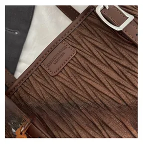 Macro d'une texture en daim matelassé marron foncé avec bandoulière et boucle en argent