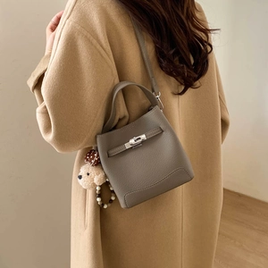 Macro view of grey pebble leather bucket bag featuring silver buckle and cute bear charm