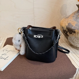 Détail du sac seau en cuir grainé noir avec fermoir rotatif argenté et bijou lapin