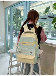 Detail of multi-pocket canvas backpack with cute graphics and pink plush charm