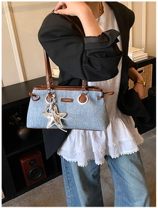 Détail du sac bandoulière en jean bleu avec finitions cuir brun et breloque étoile argent