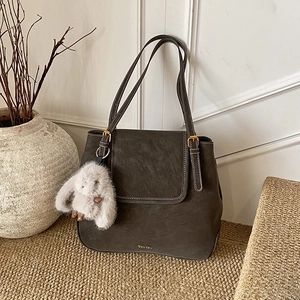 Detailed view of vintage brown leather bucket bag with stitching and rabbit charm