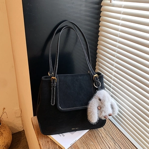 Close-up of black suede tote bag with white stitching and plush bunny charm detail