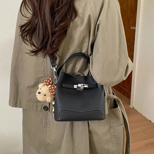 Detail of black pebbled leather bucket bag with silver turn-lock and teddy bear charm