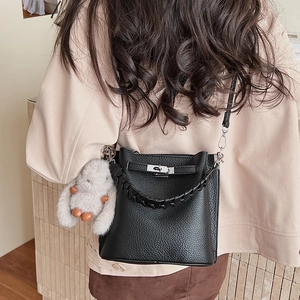Détail d'un sac seau en cuir grainé noir avec fermoir métallique et pendentif lapin doux