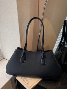 Minimalist black lychee texture leather tote bag with long shoulder straps on a desk