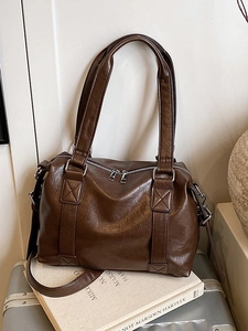 Retro deep brown Boston bag in glossy PU leather with silver hardware on a suitcase