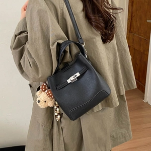 Close-up of black lychee grain leather bucket bag with silver clasp and bear charm