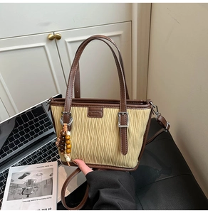 Detail of retro beige and brown bucket bag with beaded charm and adjustable strap