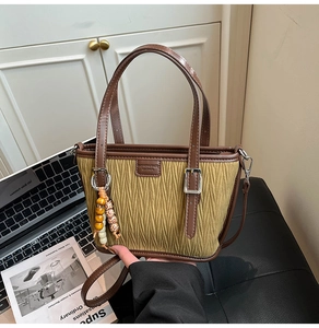 Detail of olive green pleated tote bag with vintage leather trim and wooden bead charm