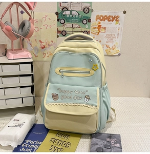 Close-up of pastel green and yellow canvas backpack with cute cartoon prints and lace detail