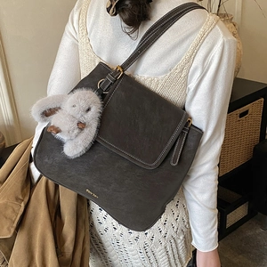 Close-up of vintage bucket bag featuring white contrast stitching and plush rabbit charm