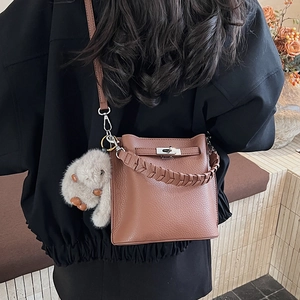 Détail du sac seau en cuir marron avec fermoir tournant argenté et breloque lapin en peluche