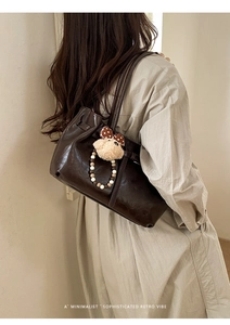 Close-up of vintage dark brown tote bag with glossy pleated texture and cute bear charm