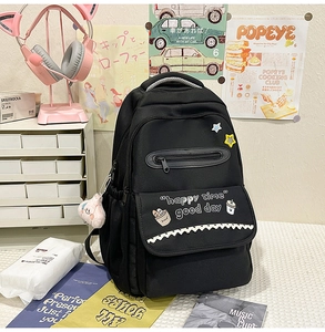 Detail of black canvas backpack featuring happy time prints and cute doll pendant