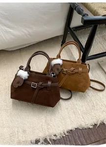 Détail de sacs à bandoulière en daim avec boucle décorative et breloque gant en peluche