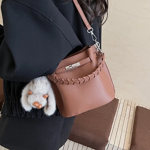 Détail du sac seau marron en cuir grainé avec anse tressée et pendentif lapin mignon