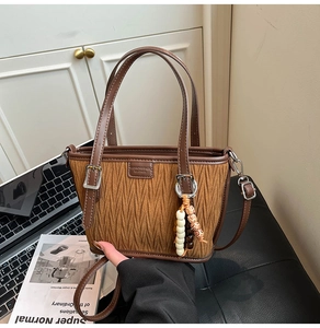 Detail of dark brown pleated bucket bag with beaded charm in a cozy lifestyle setting