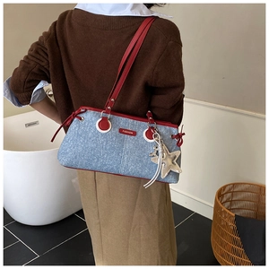 Détail du sac à bandoulière en denim avec bordure rouge et breloque étoile sur mannequin