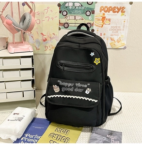 Detail of black canvas backpack featuring cute cartoon patches and happy time slogan