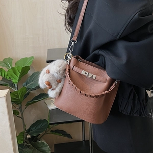 Gros plan du sac seau en cuir marron avec poignée tressée et fermoir en métal argenté